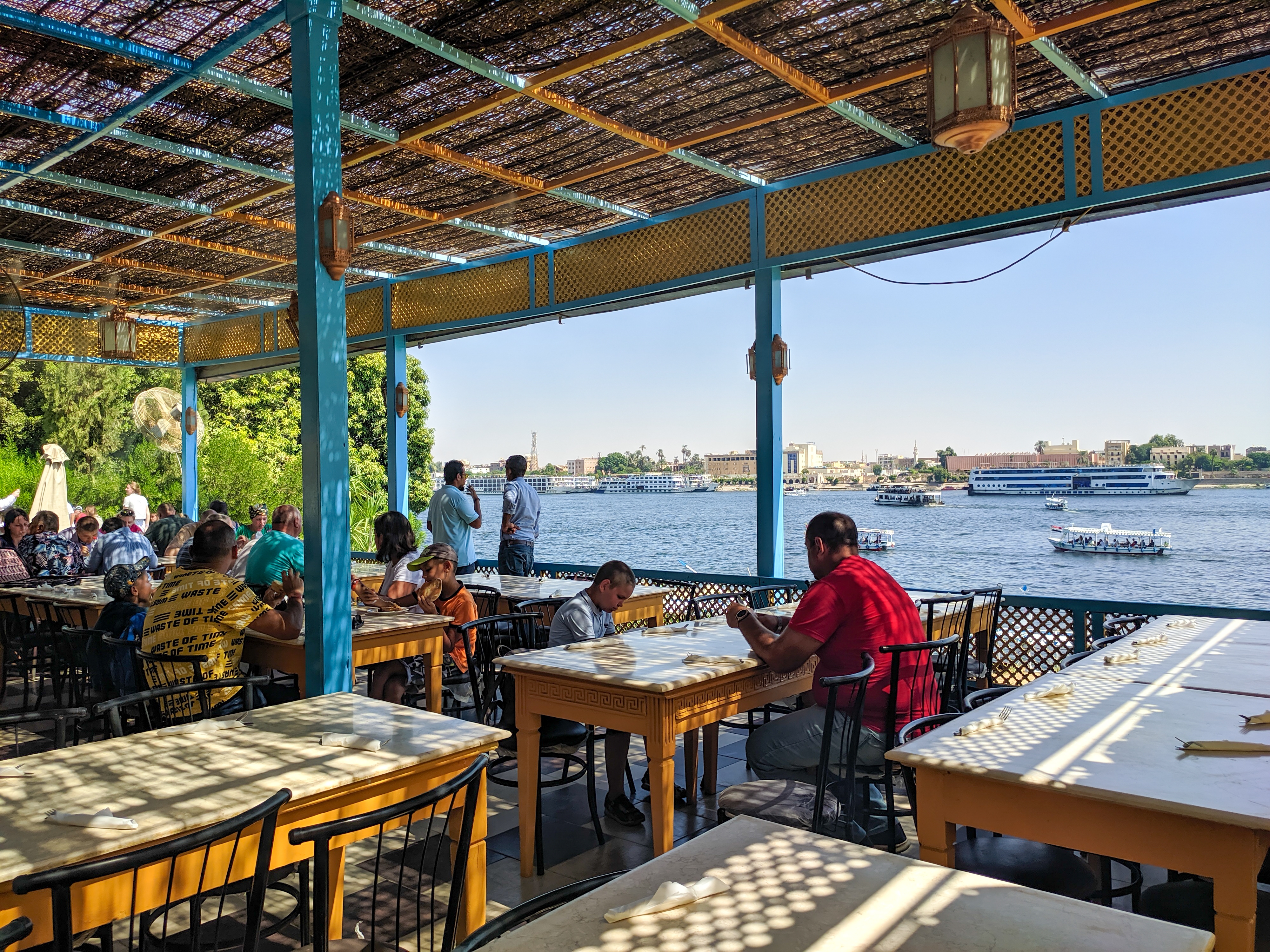: People sit in a cafe under a roof overlooking the Nile River.